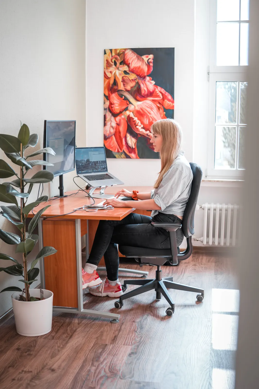 Eine Kollegin arbeitet am Schreibtisch im hellen sorum-Büro, an der Wand ein großes Blumengemälde